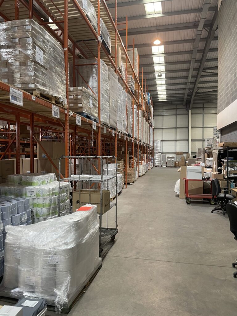 Racking bays holding wrapped pallets under warehouse lighting